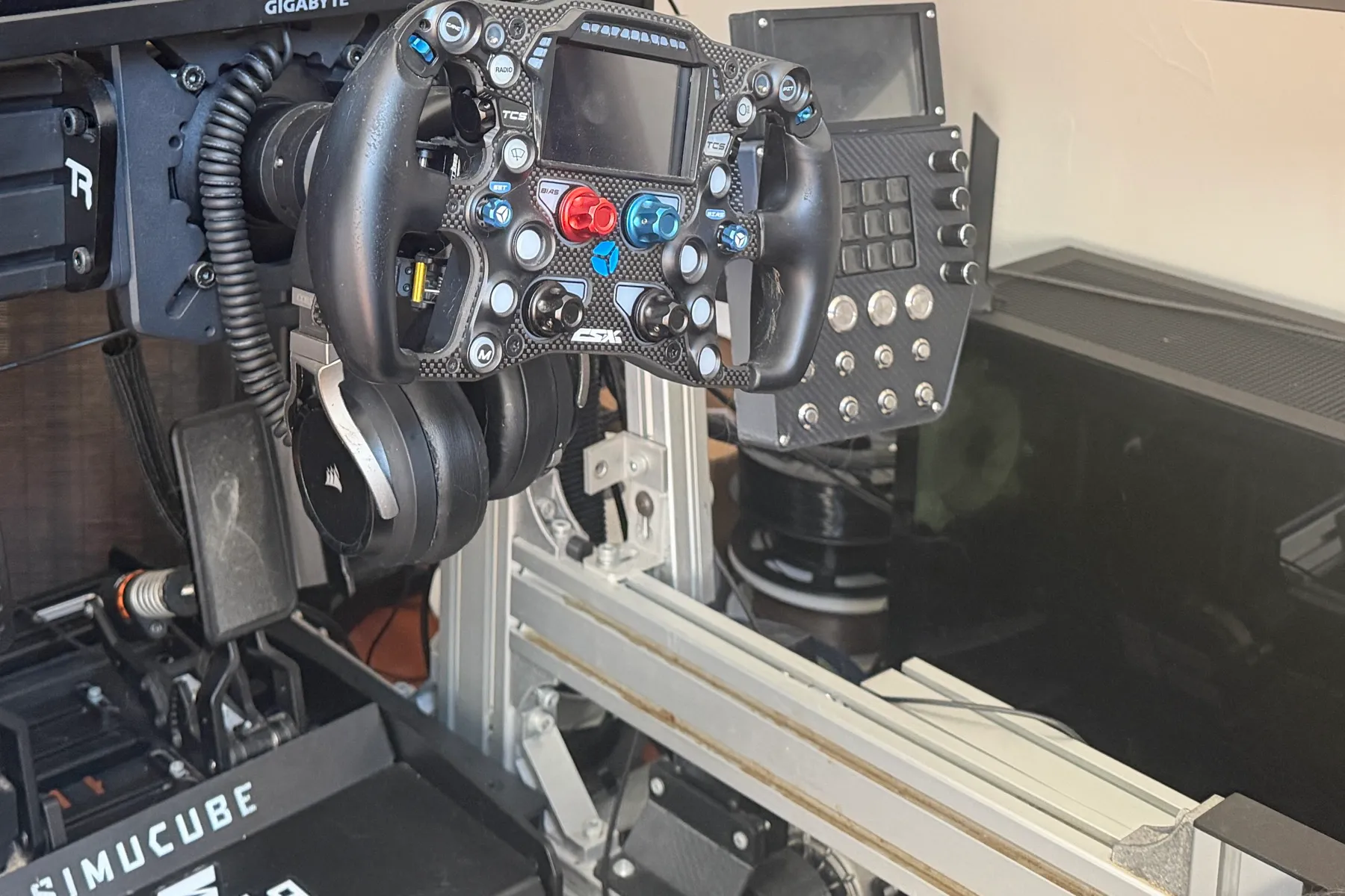 Close-up of a sim racing cockpit: formula wheel, direct drive base and aluminium profile chassis